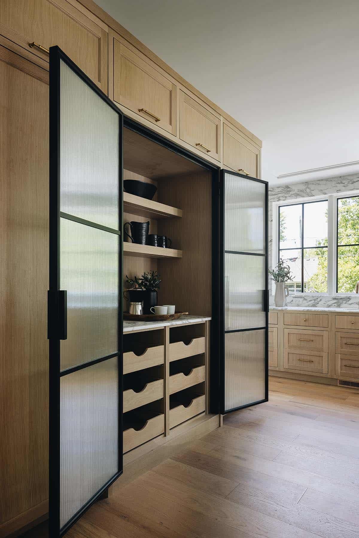 Fluted glass pantry doors open to reveal coffee station with black dishware and drawers
