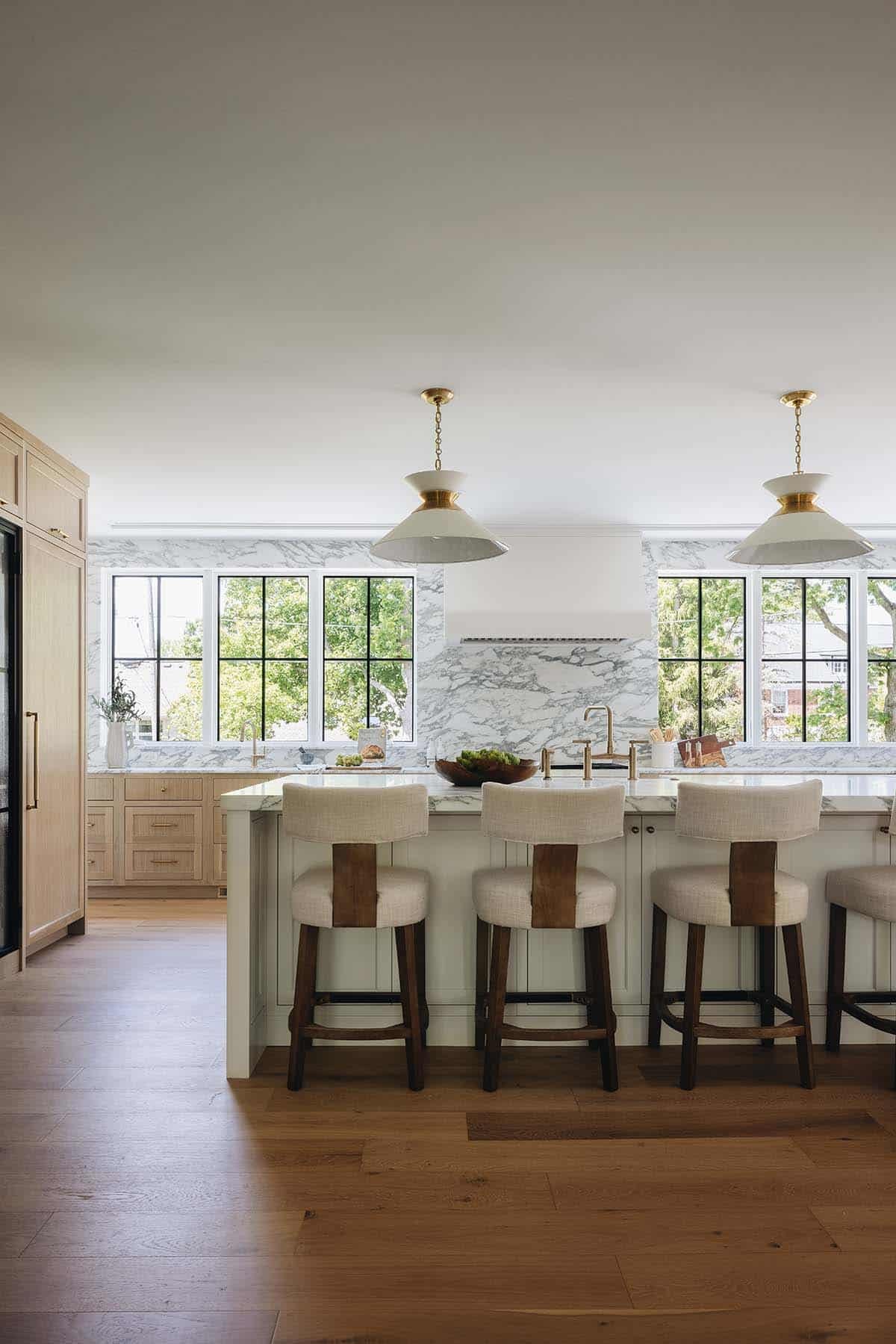 Kitchen counter stools facing marble backsplash and steel windows