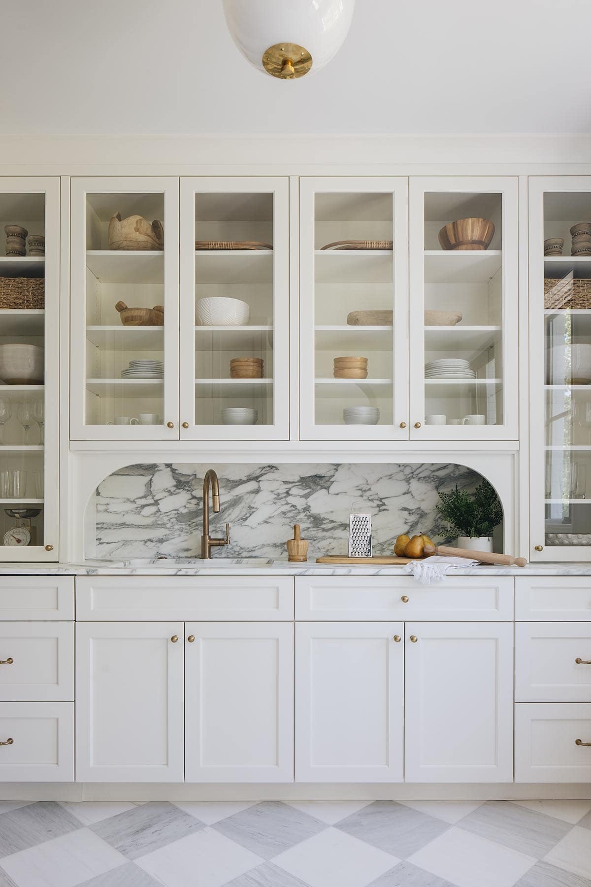 Butlers pantry with glass front cabinets and marble alcove sink