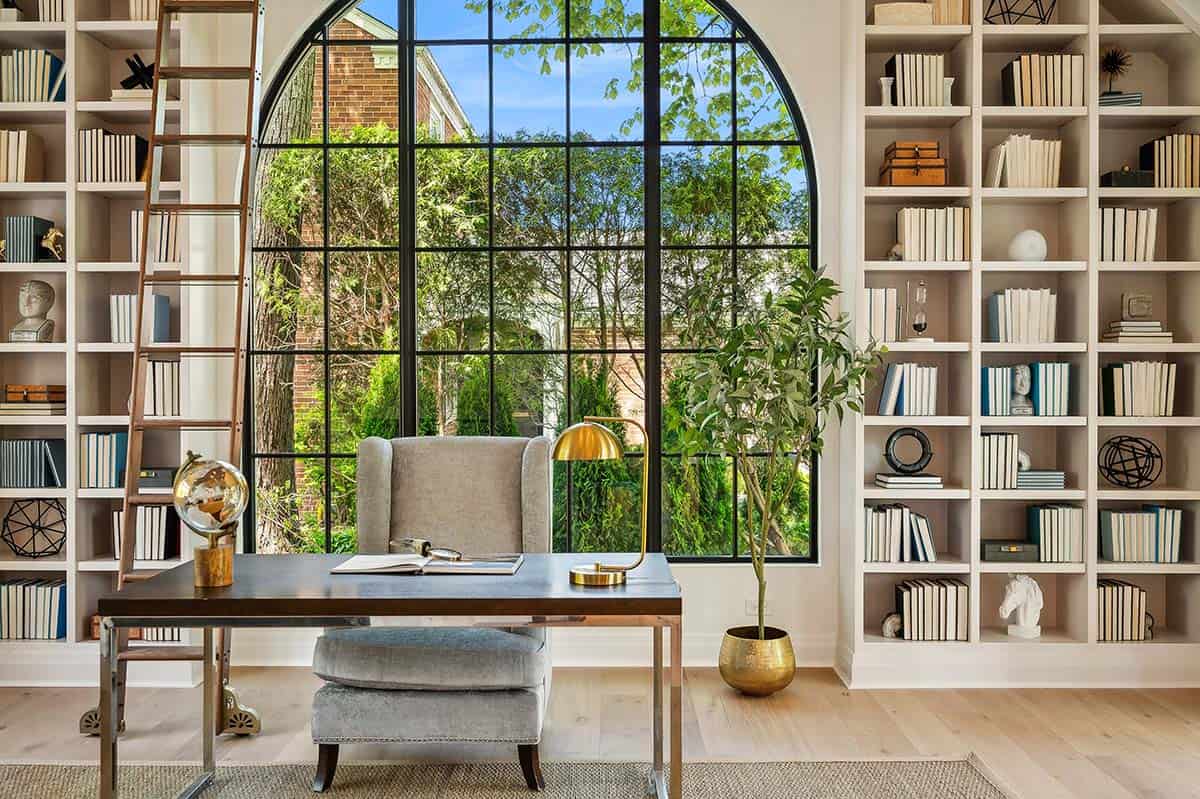 Home office with arched window and built in bookshelves