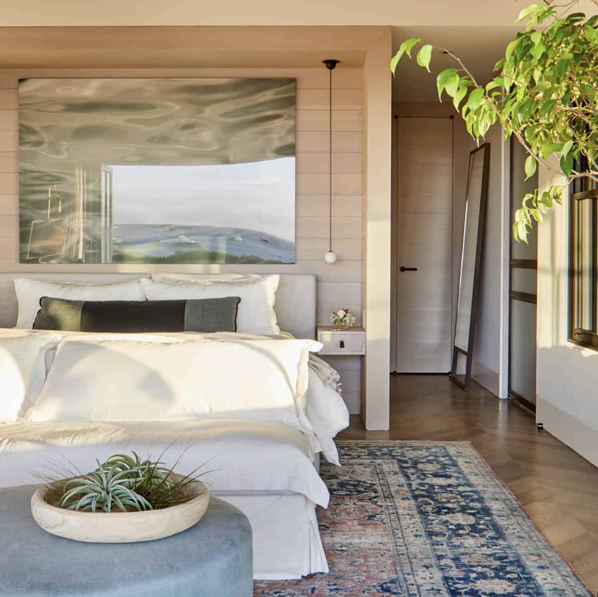 beach style bedroom with a bed, artwork and ottoman with a bowl