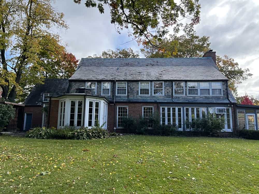 Rear exterior of stone and brick manor home before renovation begins