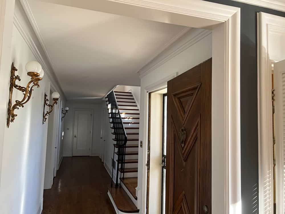 Original entry hallway with wood staircase and brass wall sconces