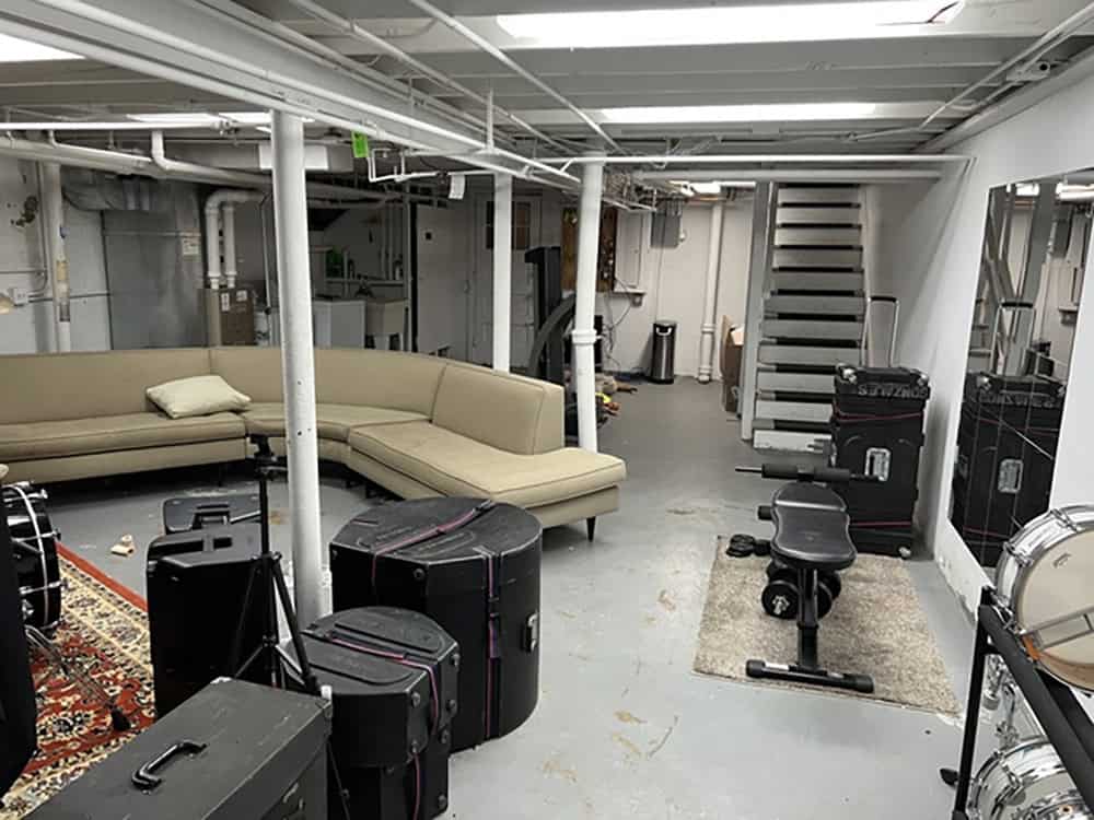 Unfinished basement space with seating and equipment before renovation