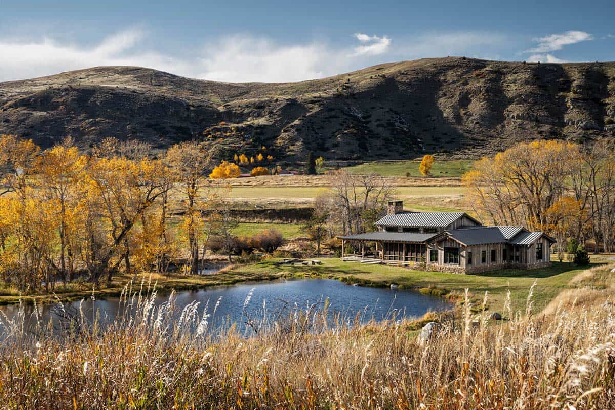 Aerial view of Boulder Retreat Ranch beside a fishing pond with autumn cottonwoods and Montana hills