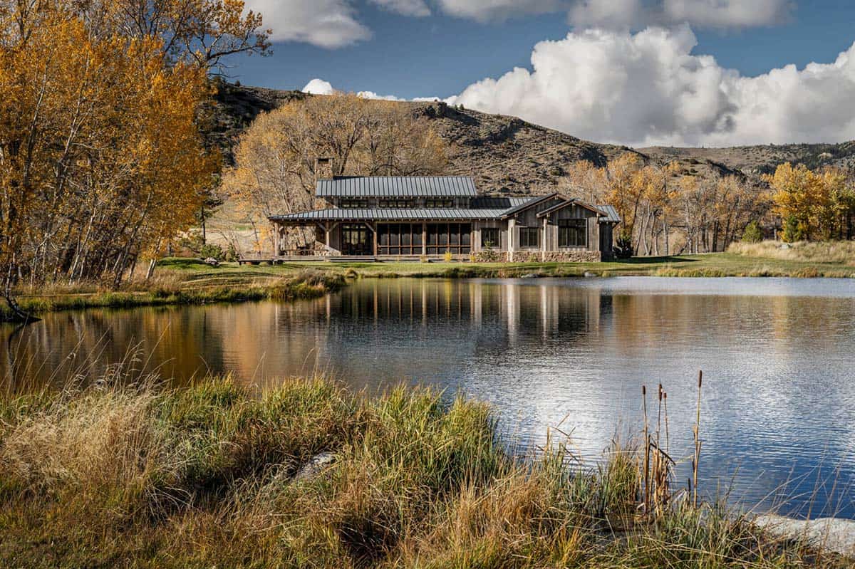 Riverside ranch home reflected in a calm pond surrounded by fall foliage
