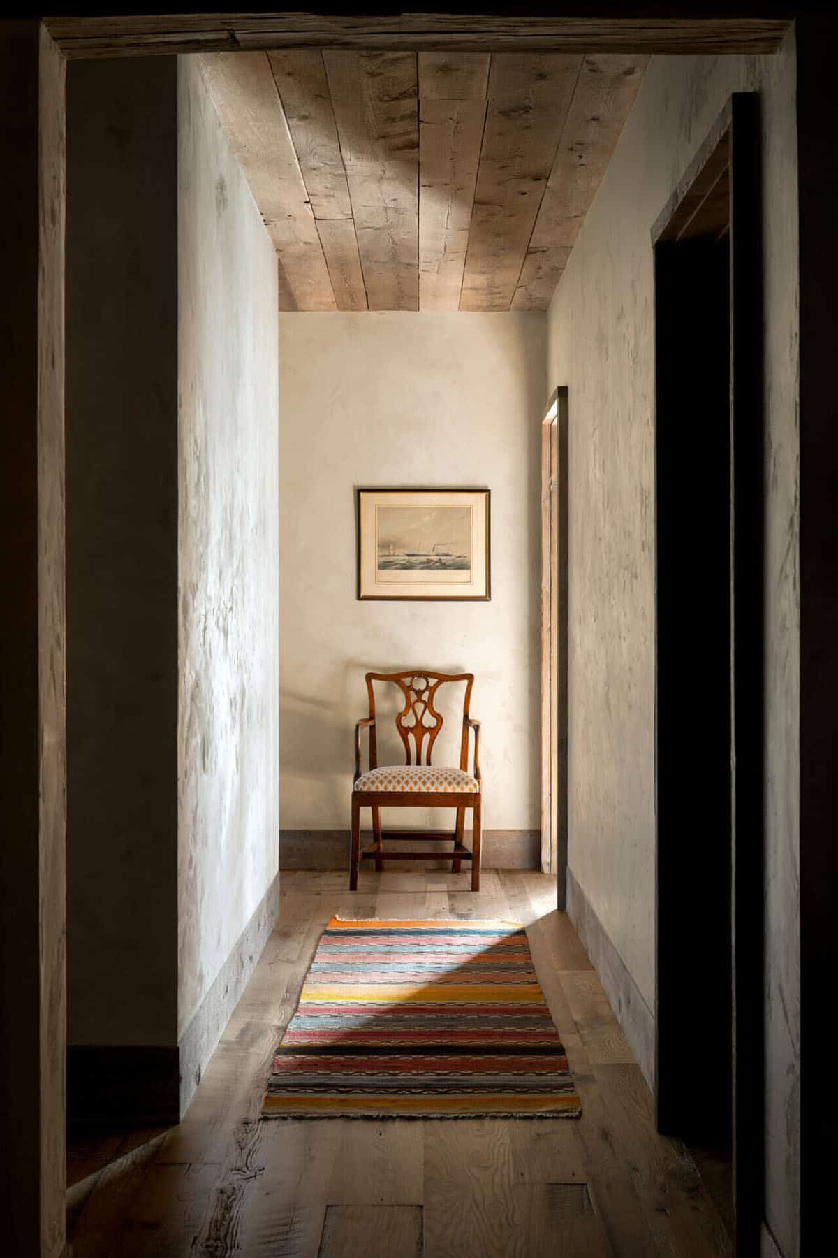 Narrow hallway with antique chair and striped runner rug