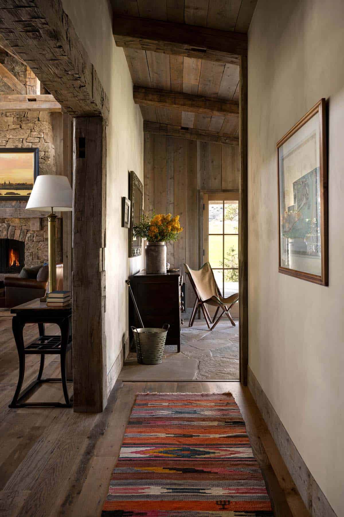 Hallway view into living room with rustic beams and layered rugs