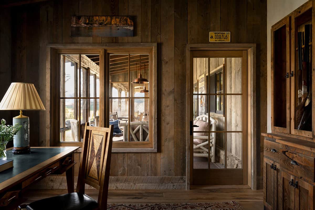Study with wood-paneled walls, desk, and porch view through windows
