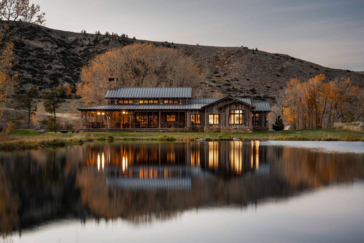Ranch home glowing at dusk, reflected in the pond