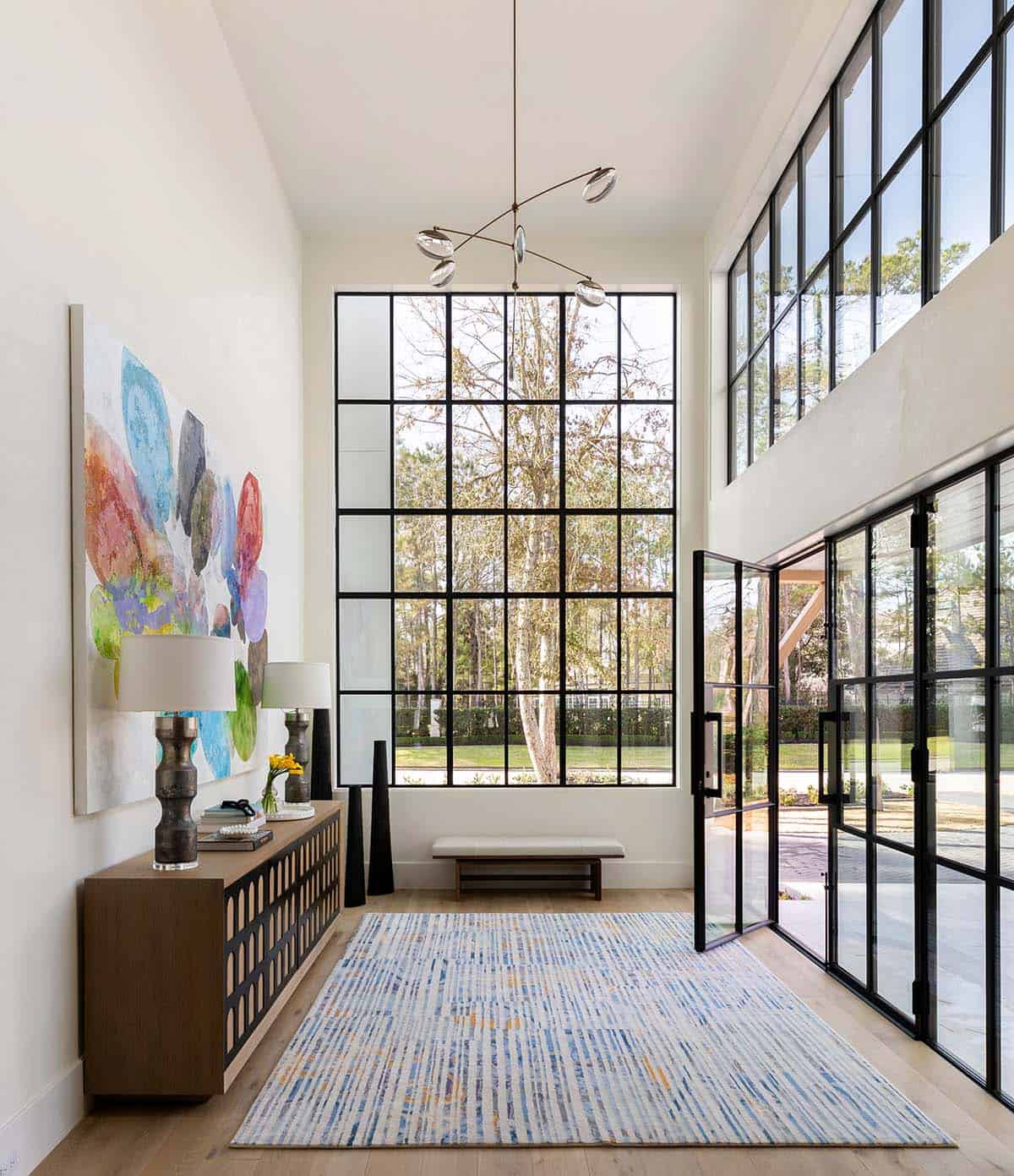 Two-story entryway with floor-to-ceiling steel windows and colorful abstract art