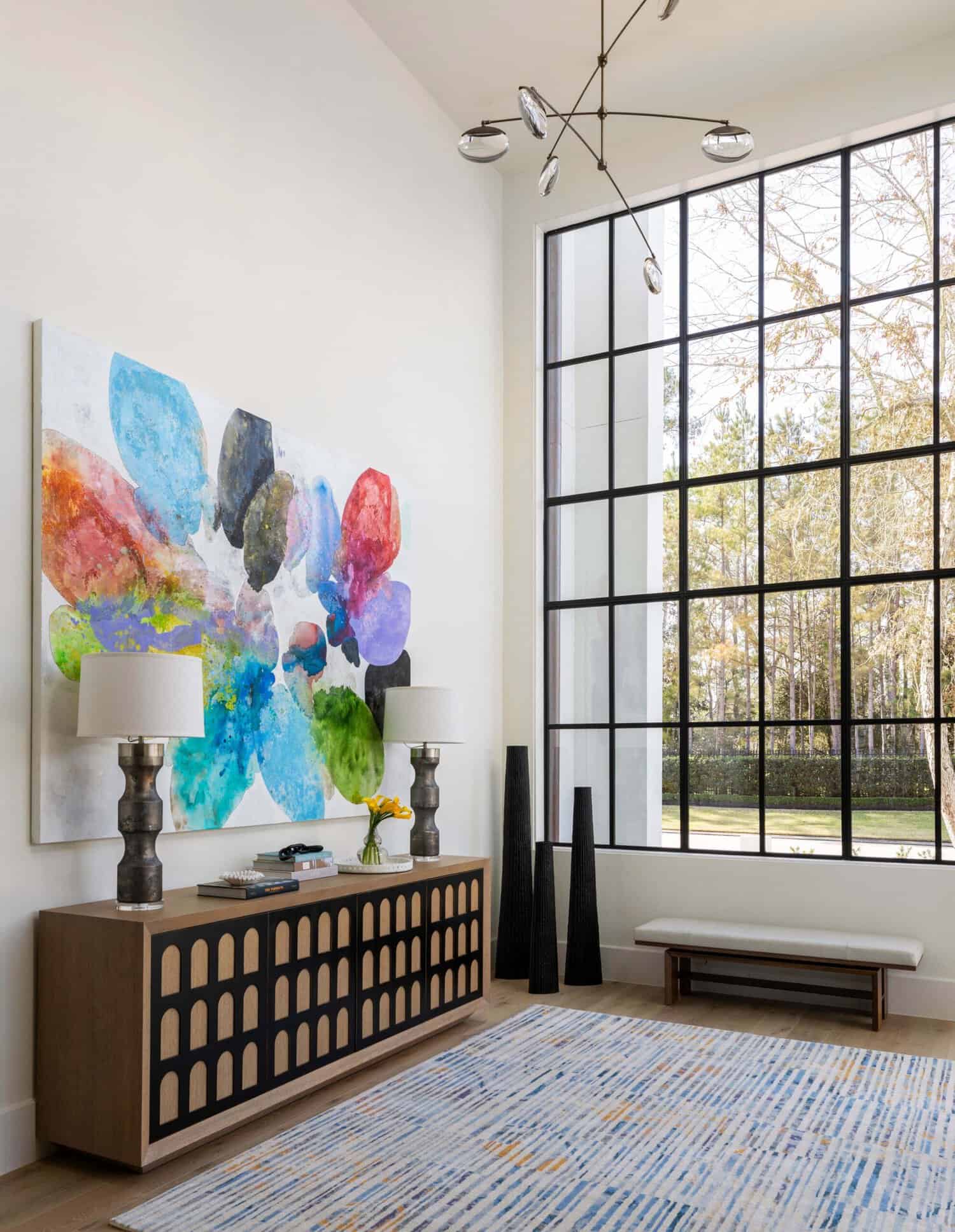Foyer with tall steel-frame windows, wood console, and mobile chandelier