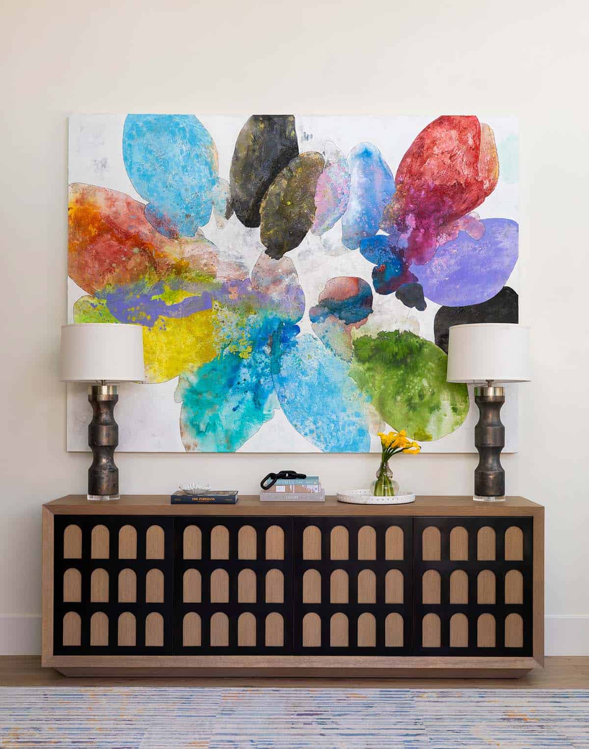 Wood and black console table with colorful abstract painting and table lamps