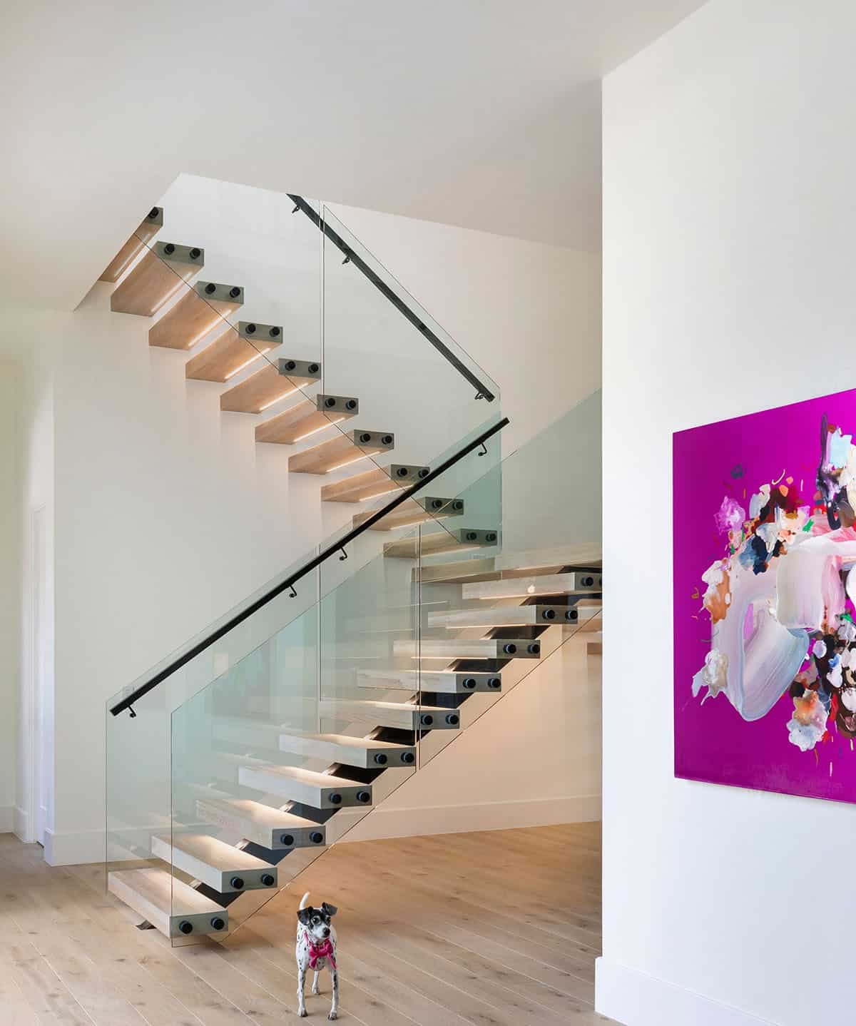 Floating wood staircase with glass railing and magenta abstract painting