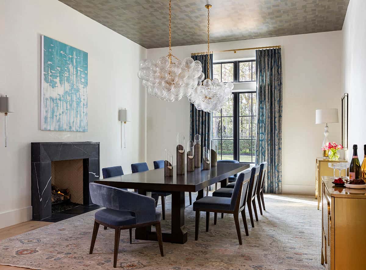 Dining room with patterned ceiling, glass bubble chandeliers, and marble fireplace