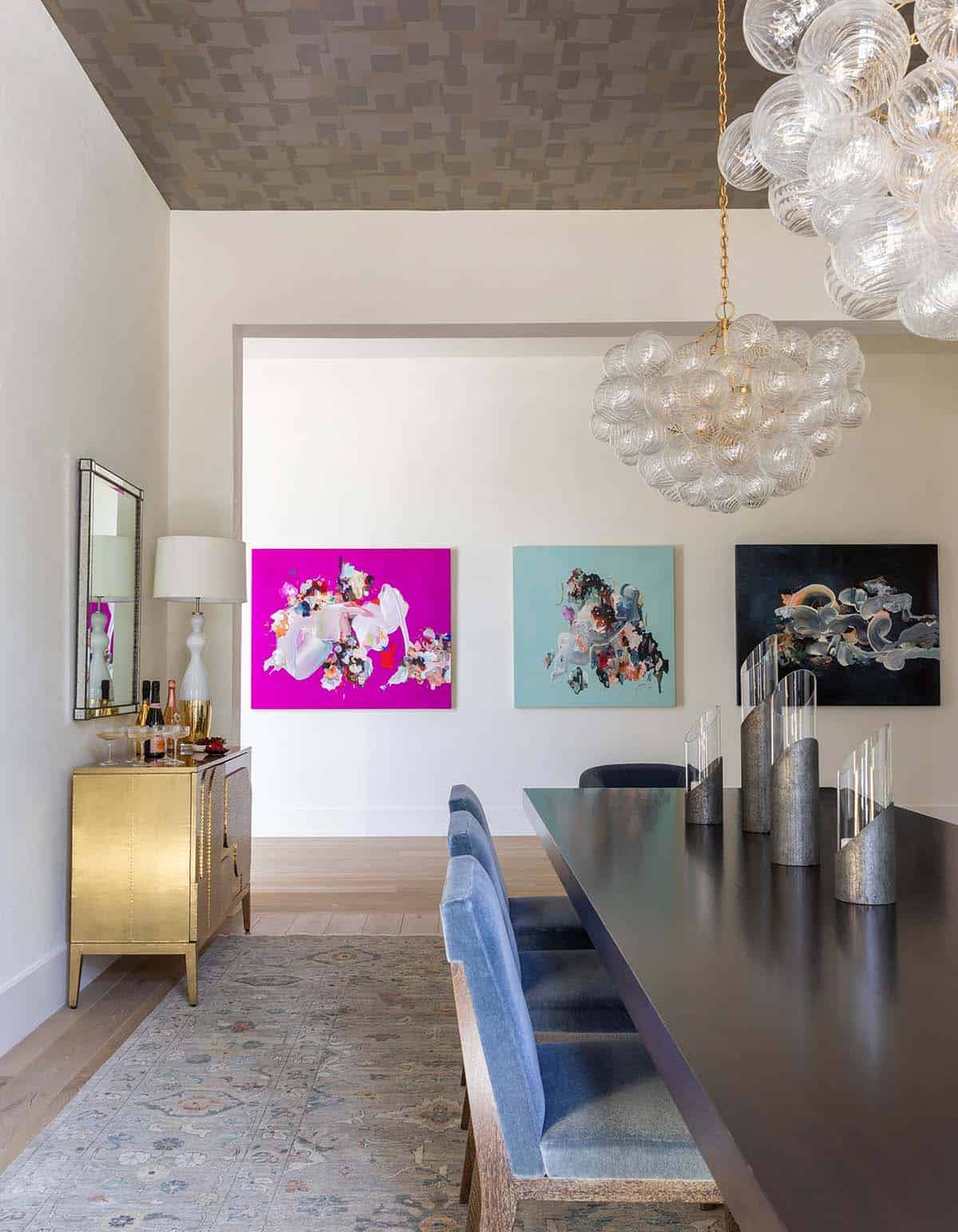 Dining room view toward gold bar cabinet and gallery of abstract paintings