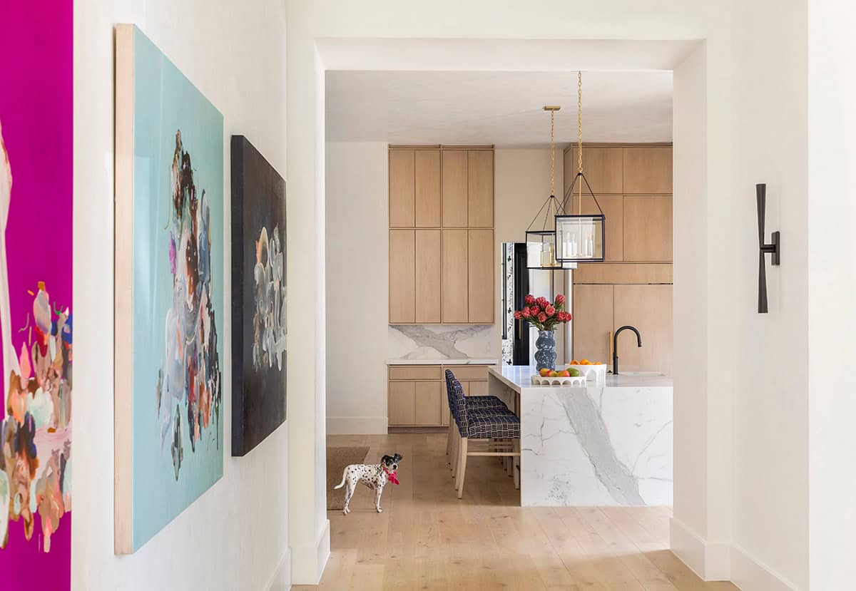 Hallway with abstract art leading into light wood kitchen