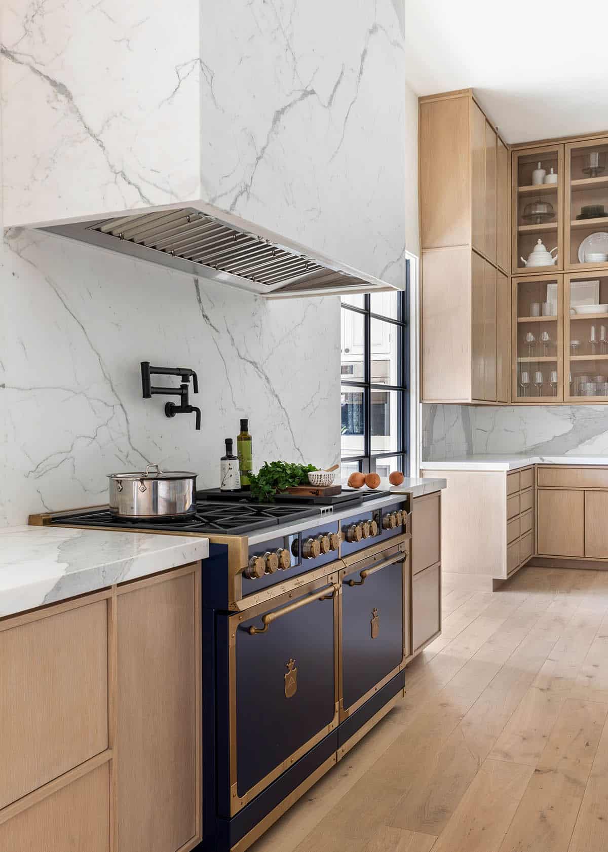 Kitchen view with marble range hood, glass-front cabinets, and gallery hallway