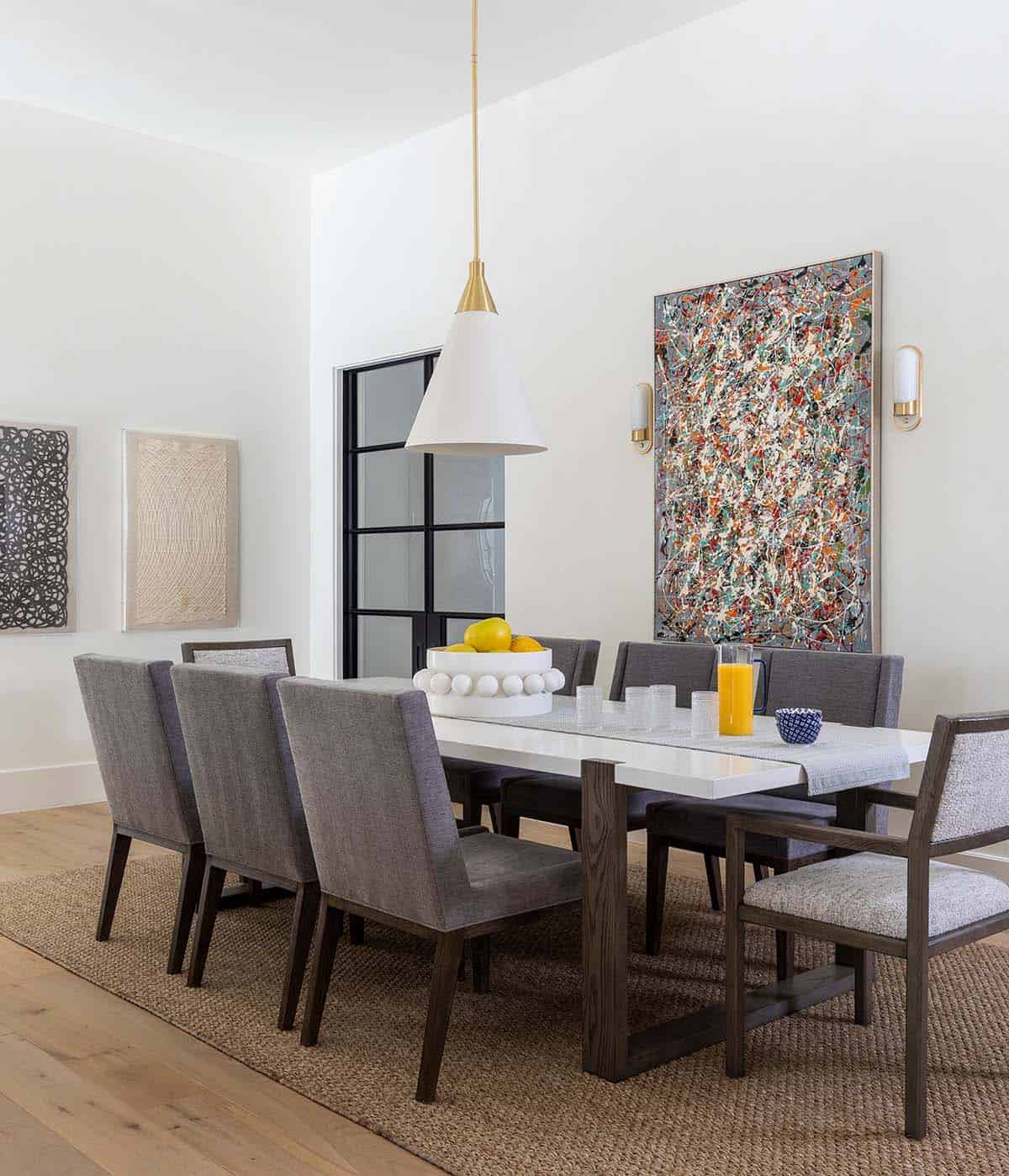 Formal dining room with gray upholstered chairs and colorful abstract art