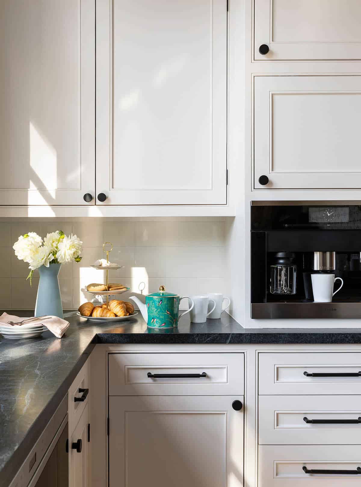 Kitchen corner with soapstone counters, black cabinet hardware, and built-in coffee maker