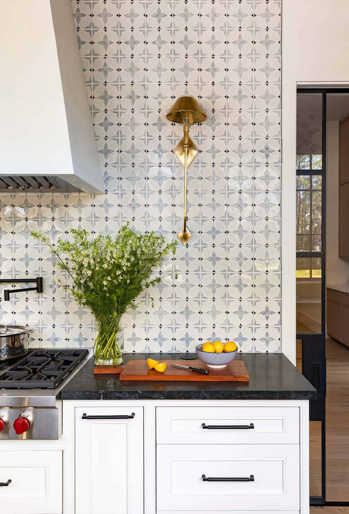 Kitchen range with patterned tile backsplash and brass wall sconce