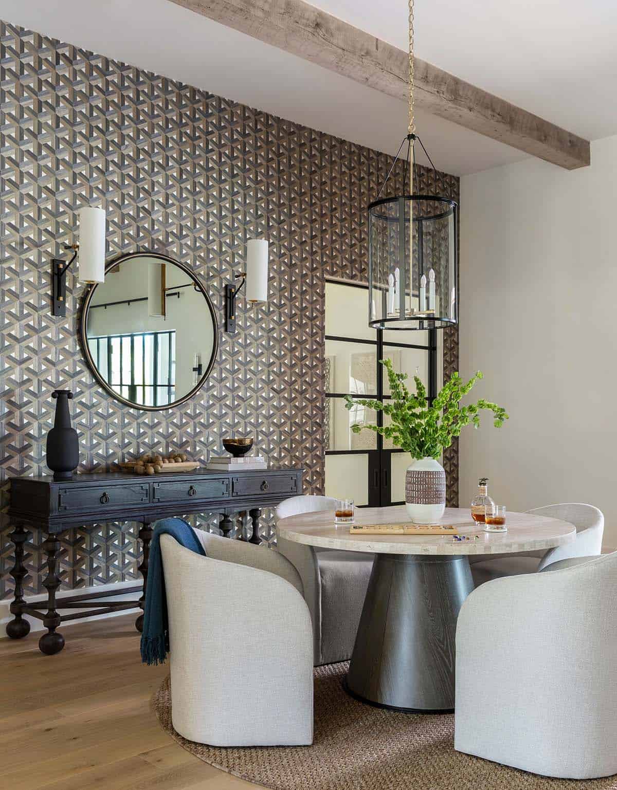 Round travertine game table with upholstered chairs and wine room view