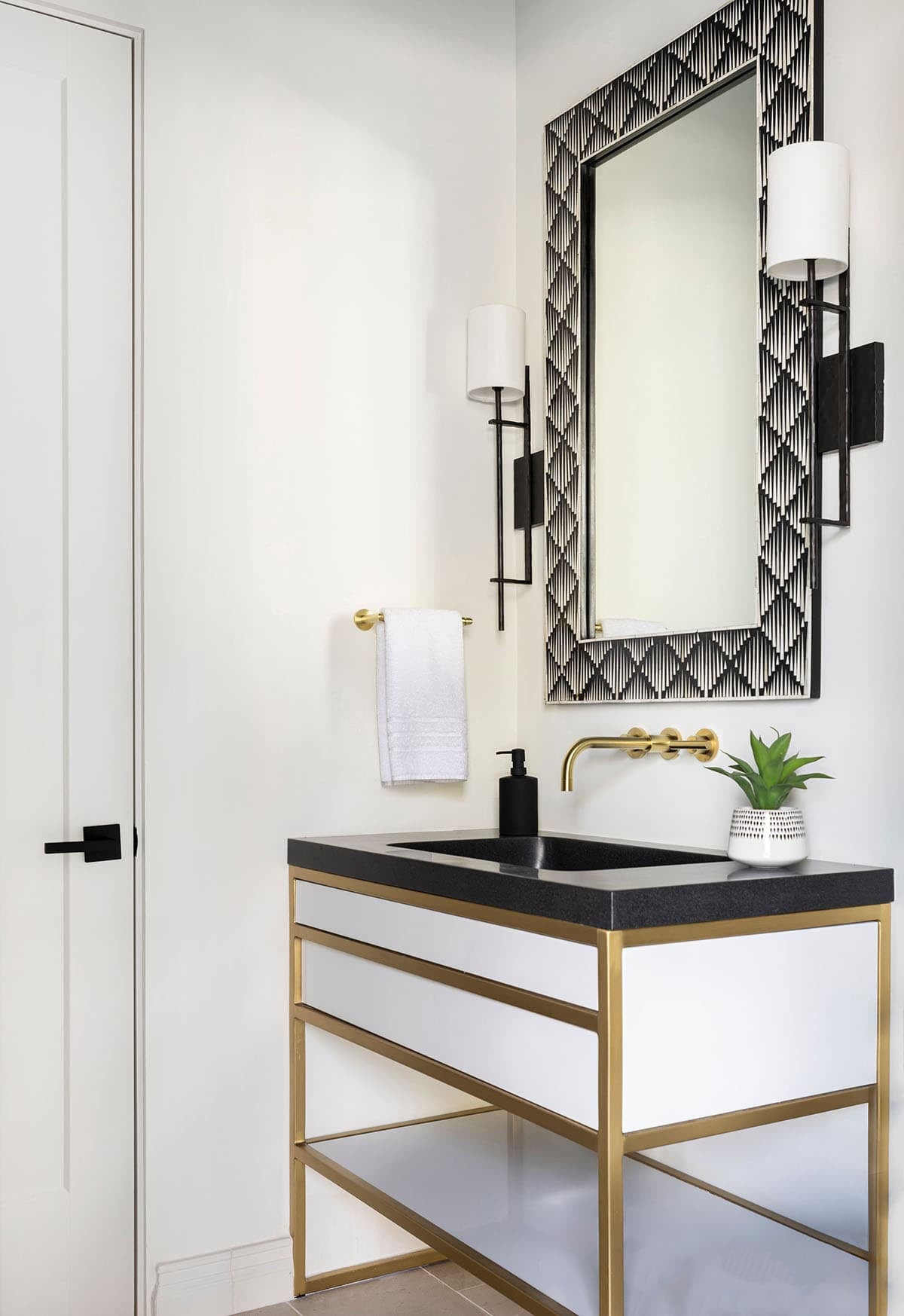 Powder room vanity with black granite top, brass frame, and patterned mirror
