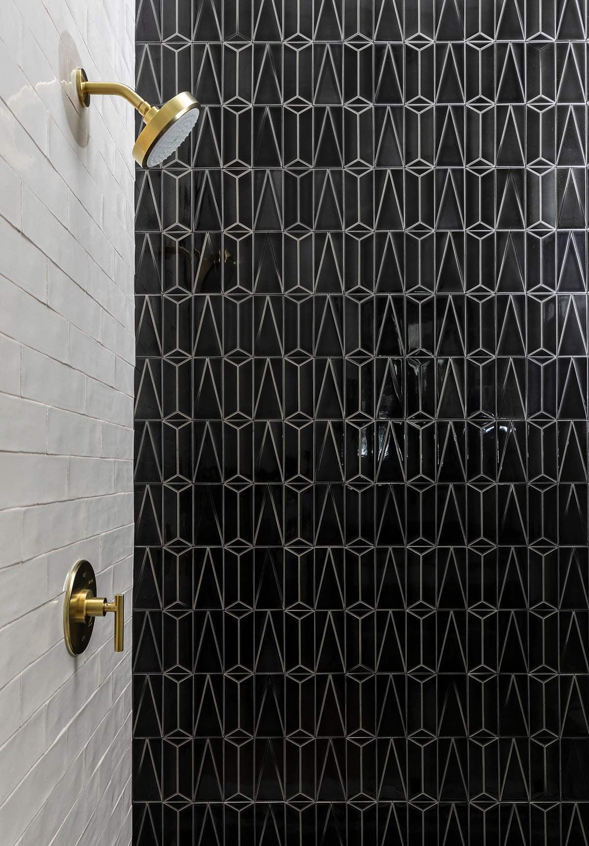 Black geometric tile shower wall with brass showerhead