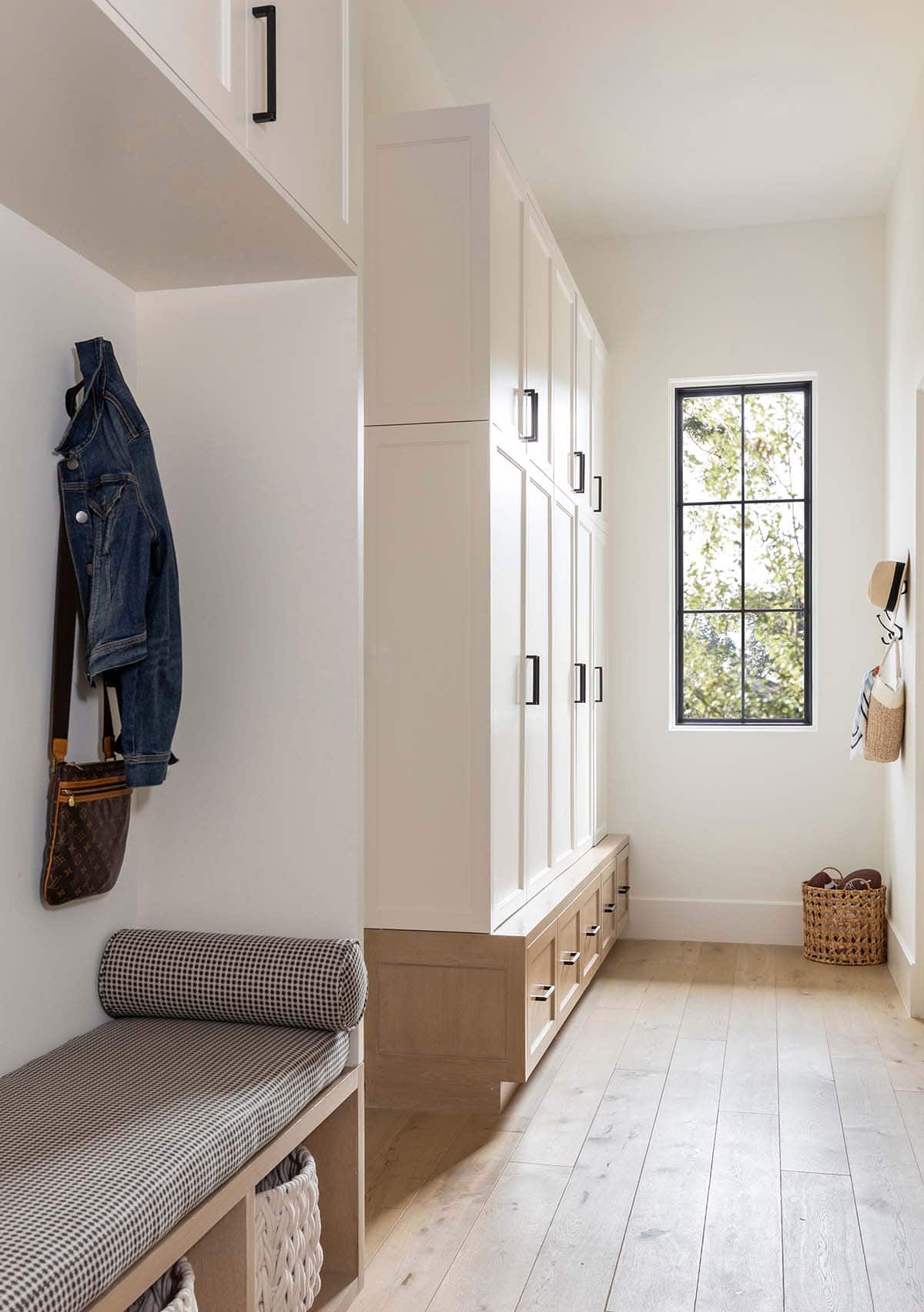 Mudroom hallway with white lockers, black hardware, and hanging bags
