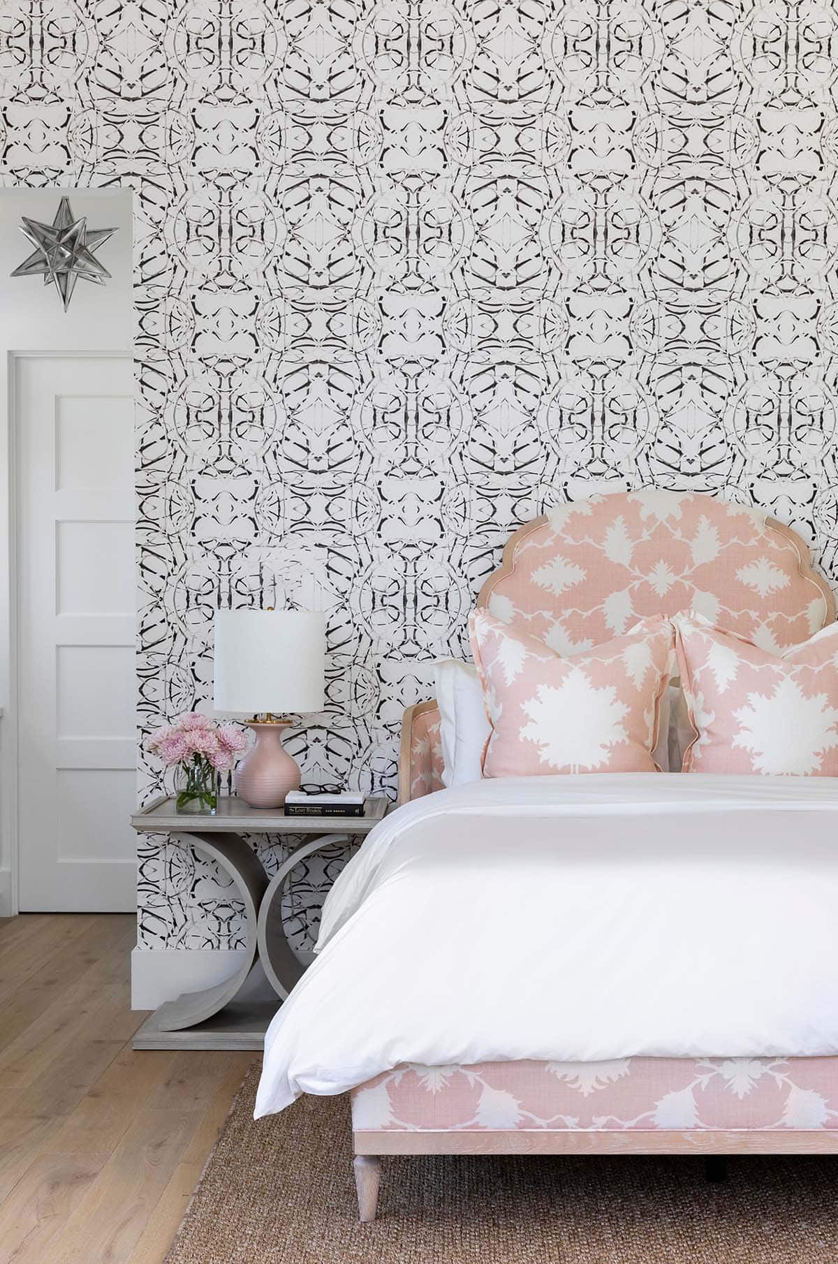 Close-up of pink patterned headboard against black and white wallpaper