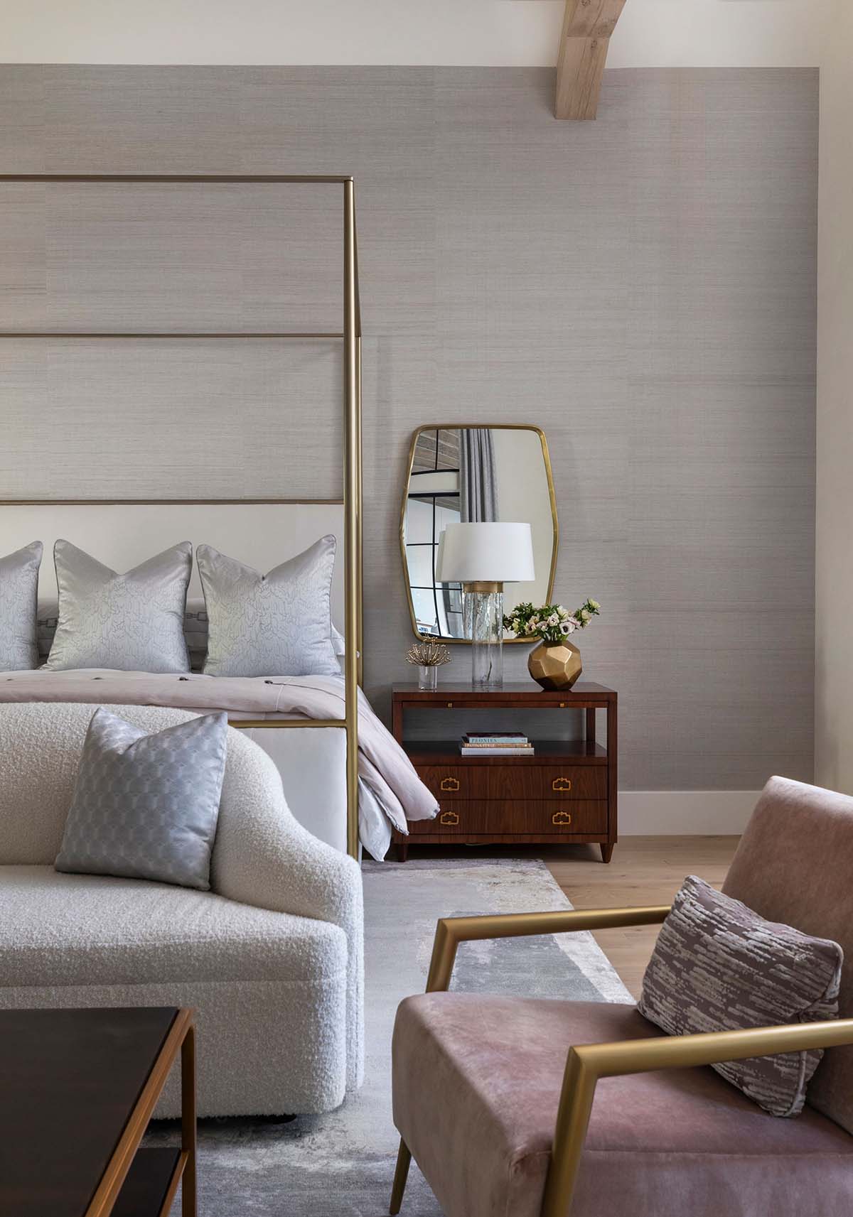 Bedside table with brass mirror, wood nightstand, and pink armchair