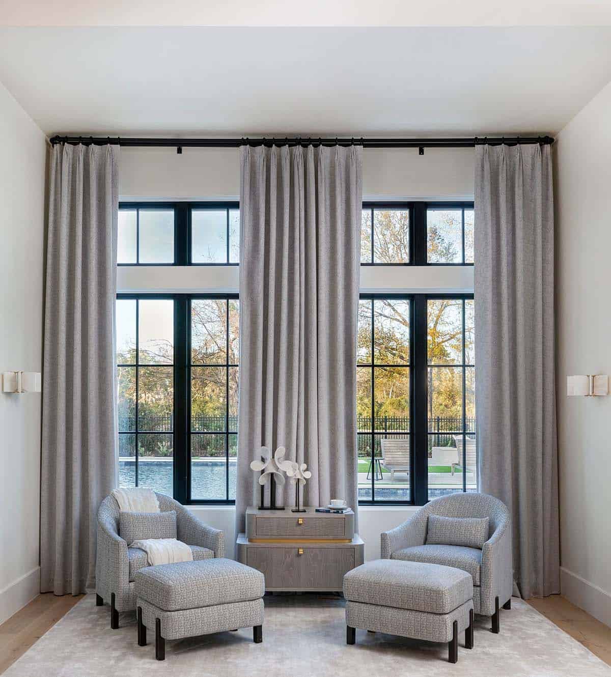 Symmetrical sitting nook with gray chairs, ottomans, and tall arched windows