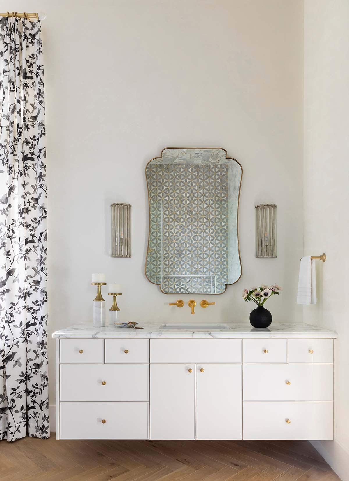 Powder room vanity with patterned mirror and floral curtain