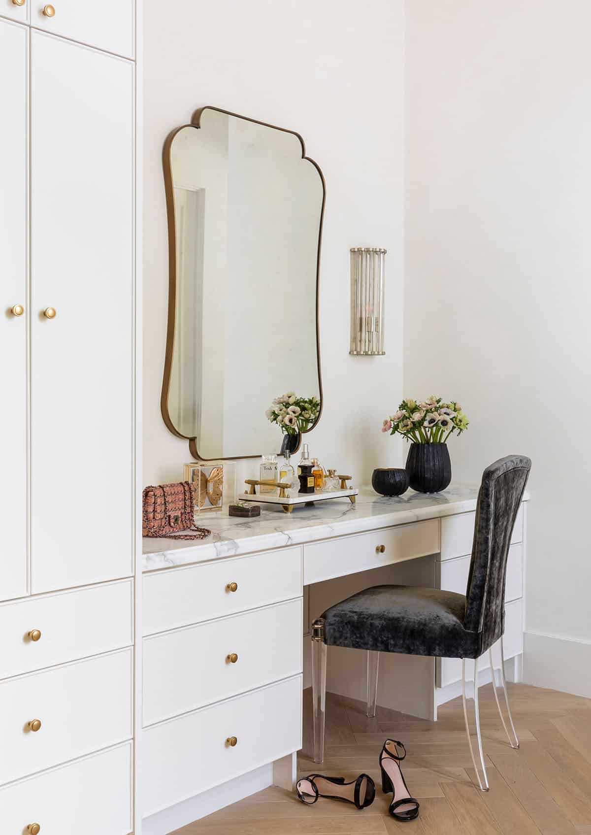 Vanity nook with scalloped mirror, marble desk, and velvet chair