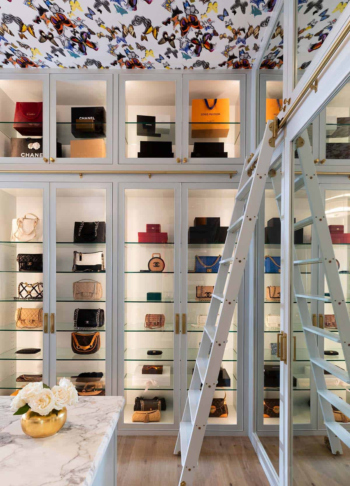 Handbag display closet with glass shelving and rolling ladder