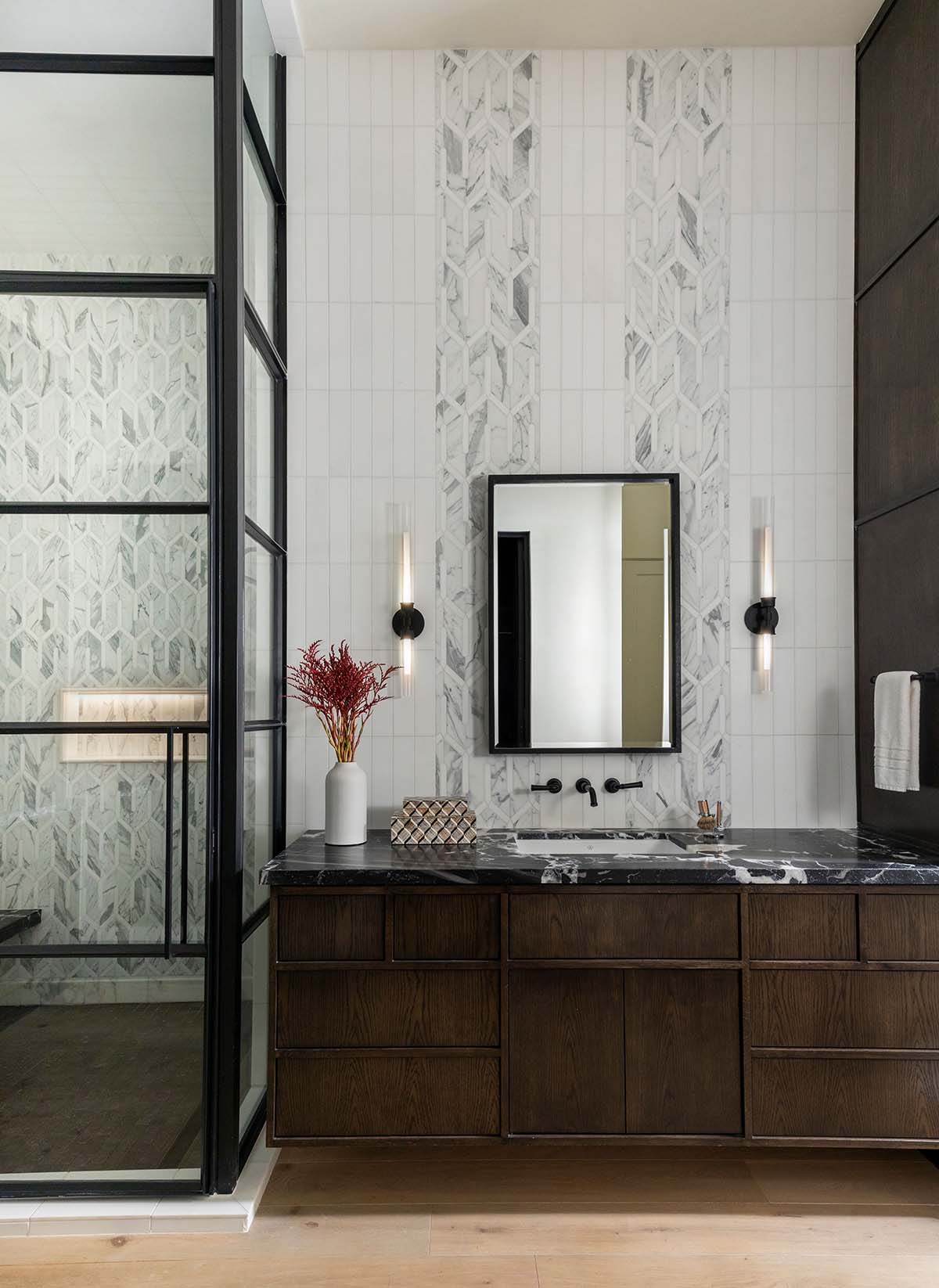 Bathroom vanity with black marble counter and geometric tile wall