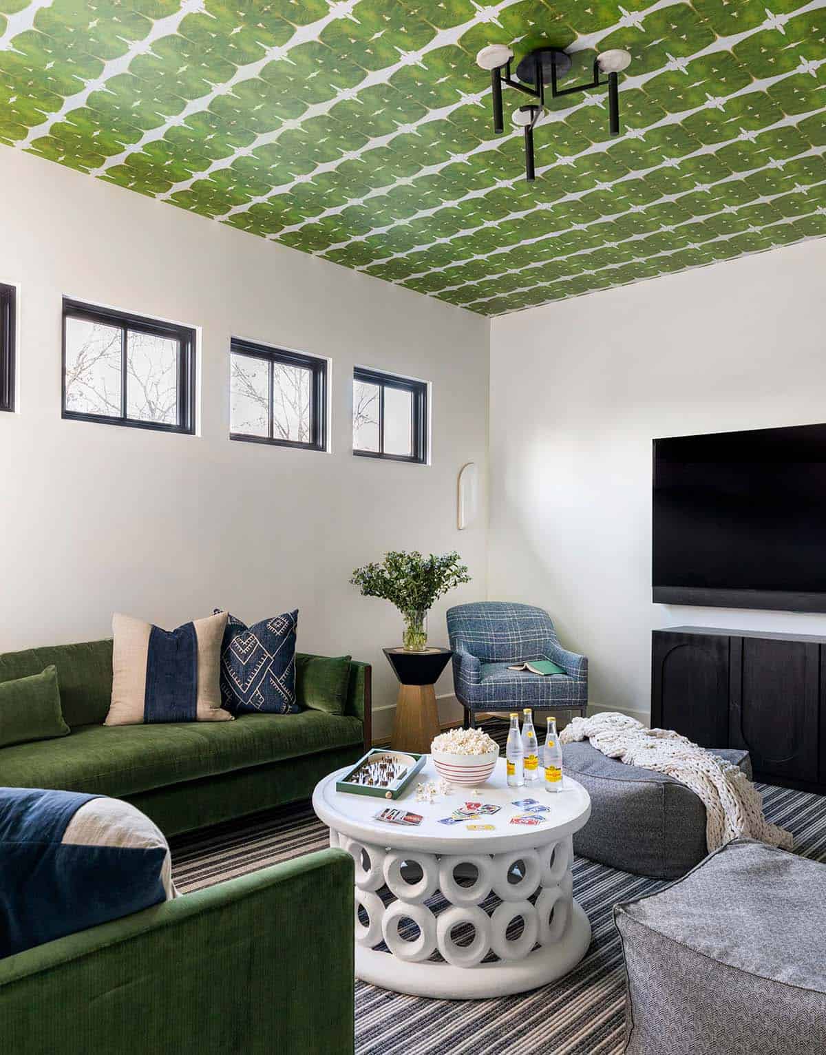 Media room with green patterned ceiling wallpaper and green velvet sofa