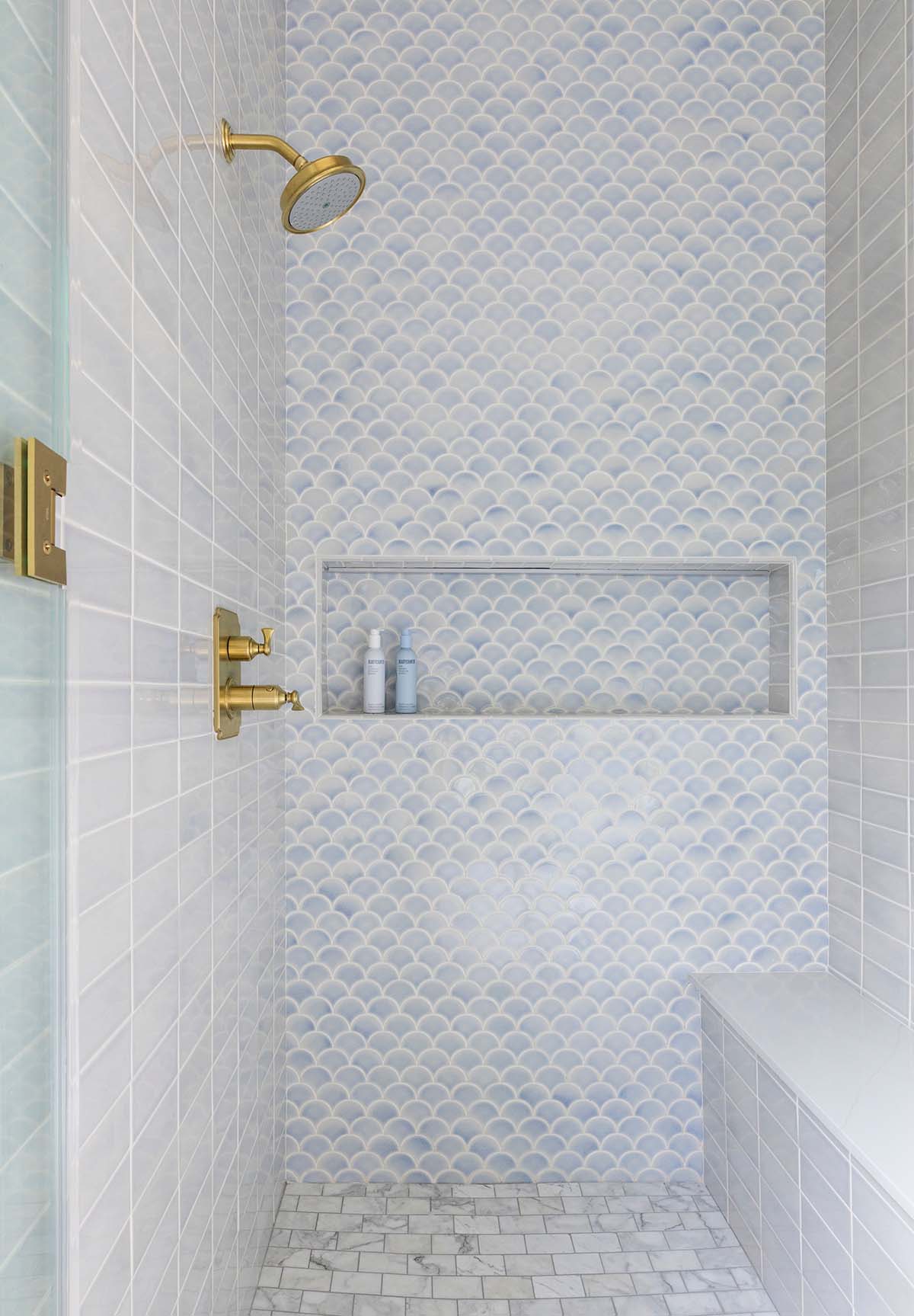 Blue scalloped tile shower with brass fixtures and built-in niche