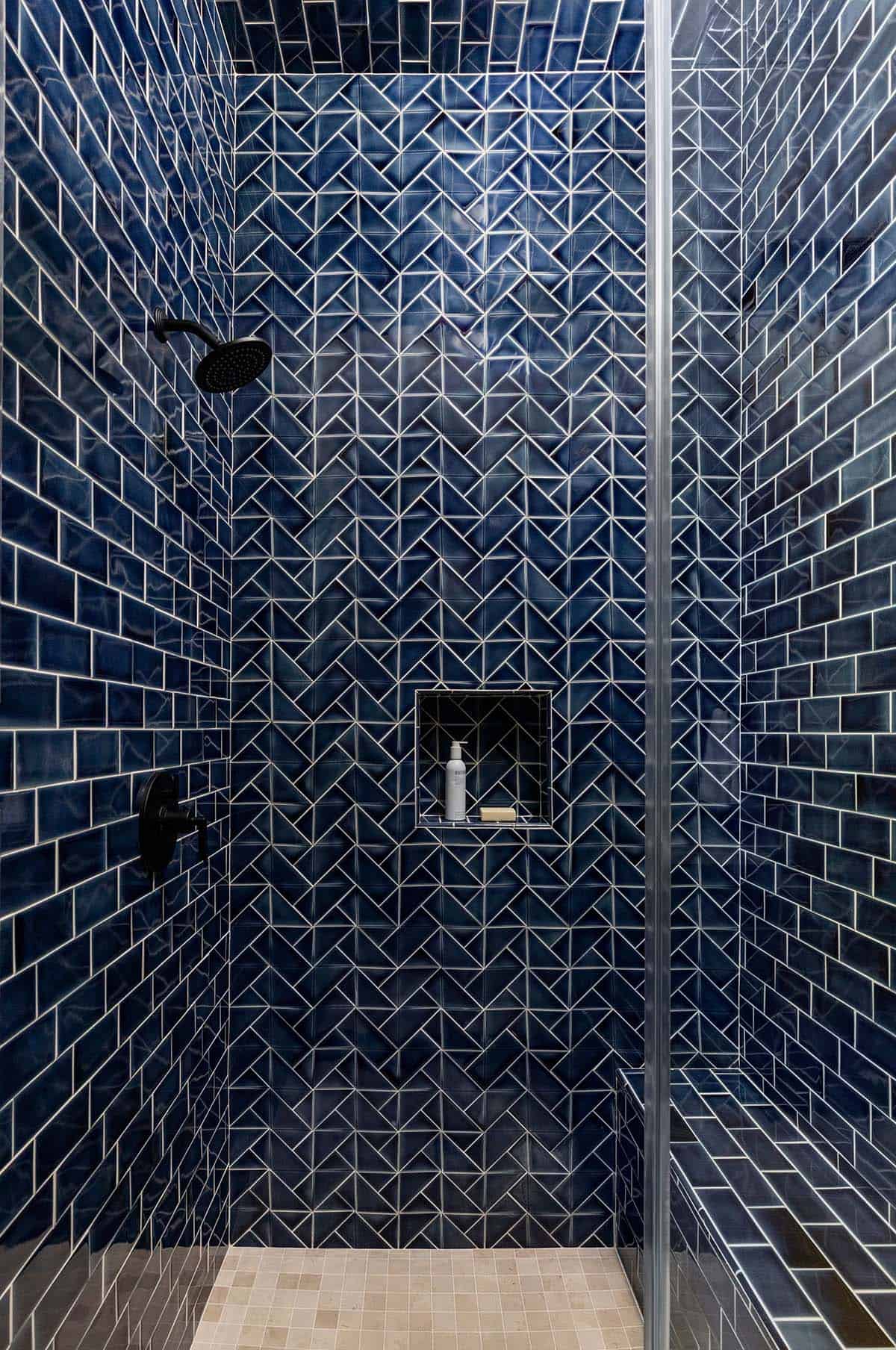 Navy chevron tile shower with black fixtures and built-in niche