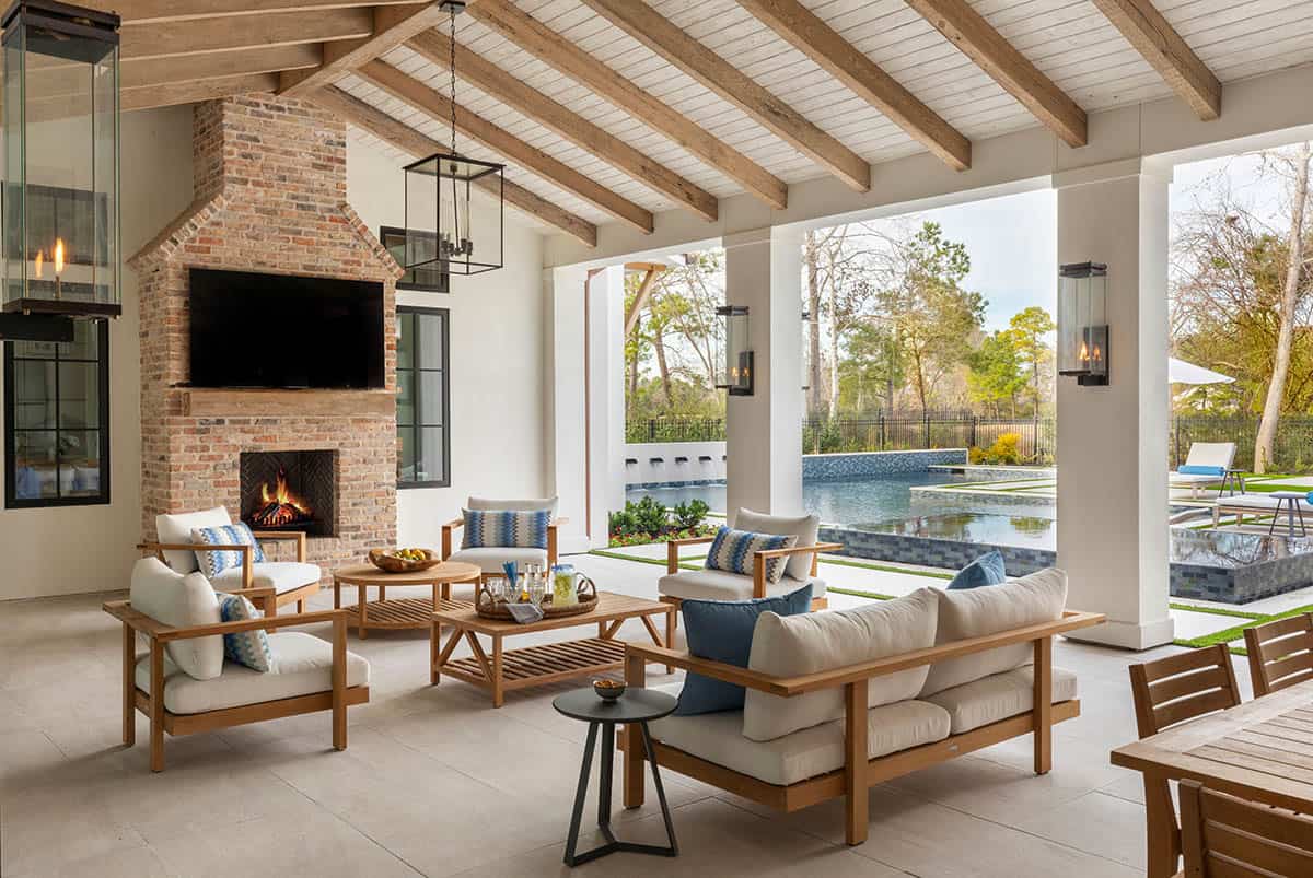 Outdoor lounge with brick fireplace, TV, and pool view