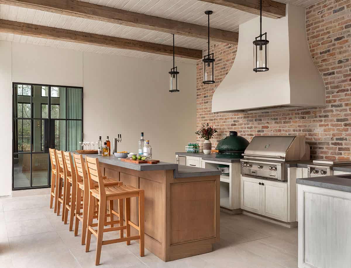 Outdoor kitchen bar with brick backsplash, wood barstools, and built-in grill
