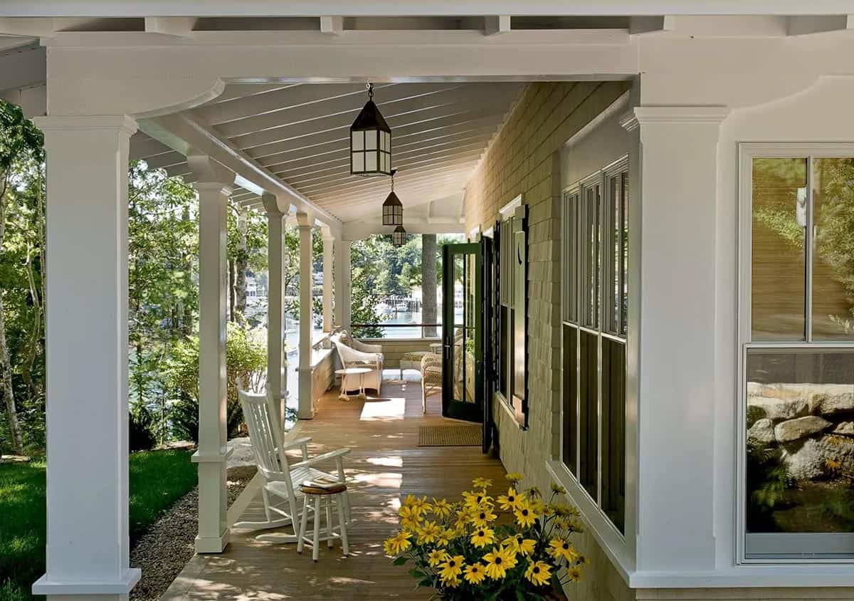Covered porch with lanterns, rocking chair, and harbor view through trees