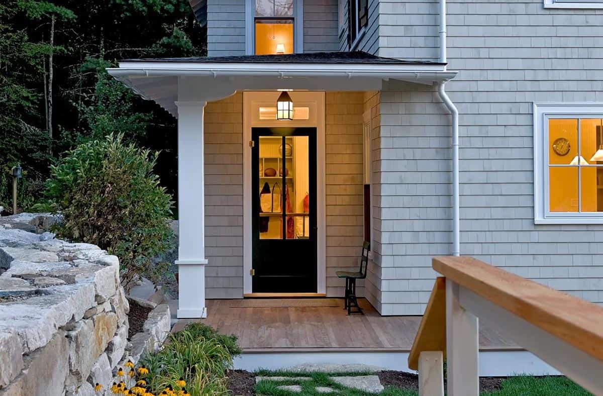 Shingled side entrance with black door lit at dusk