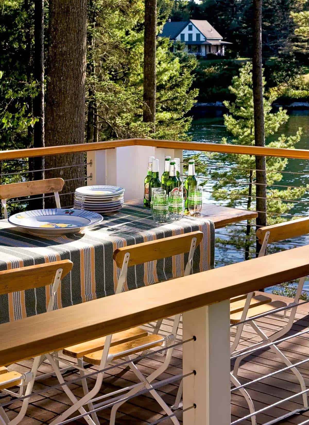 Outdoor dining table set with plates and drinks by the water