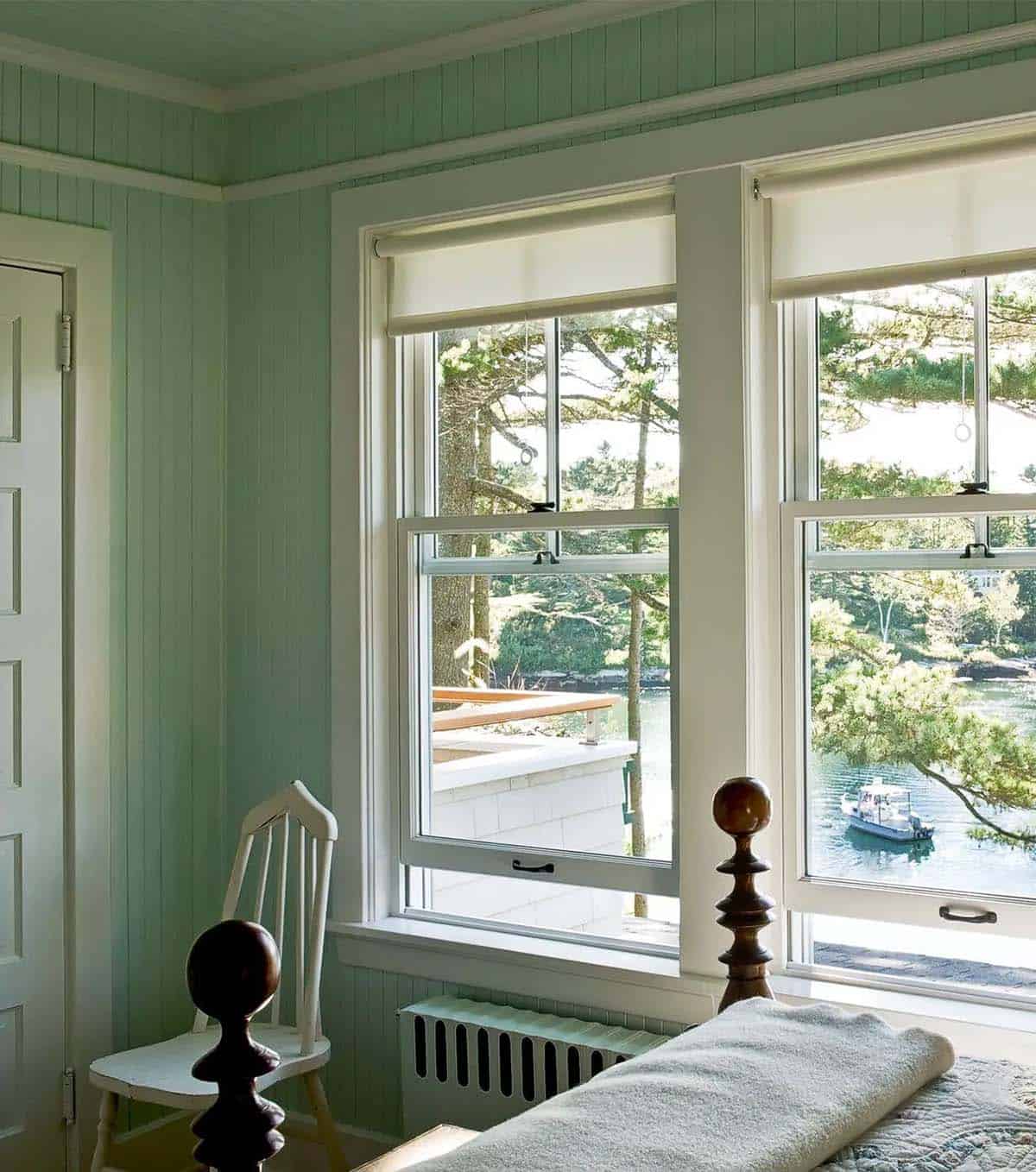 Green bedroom with twin windows overlooking the water
