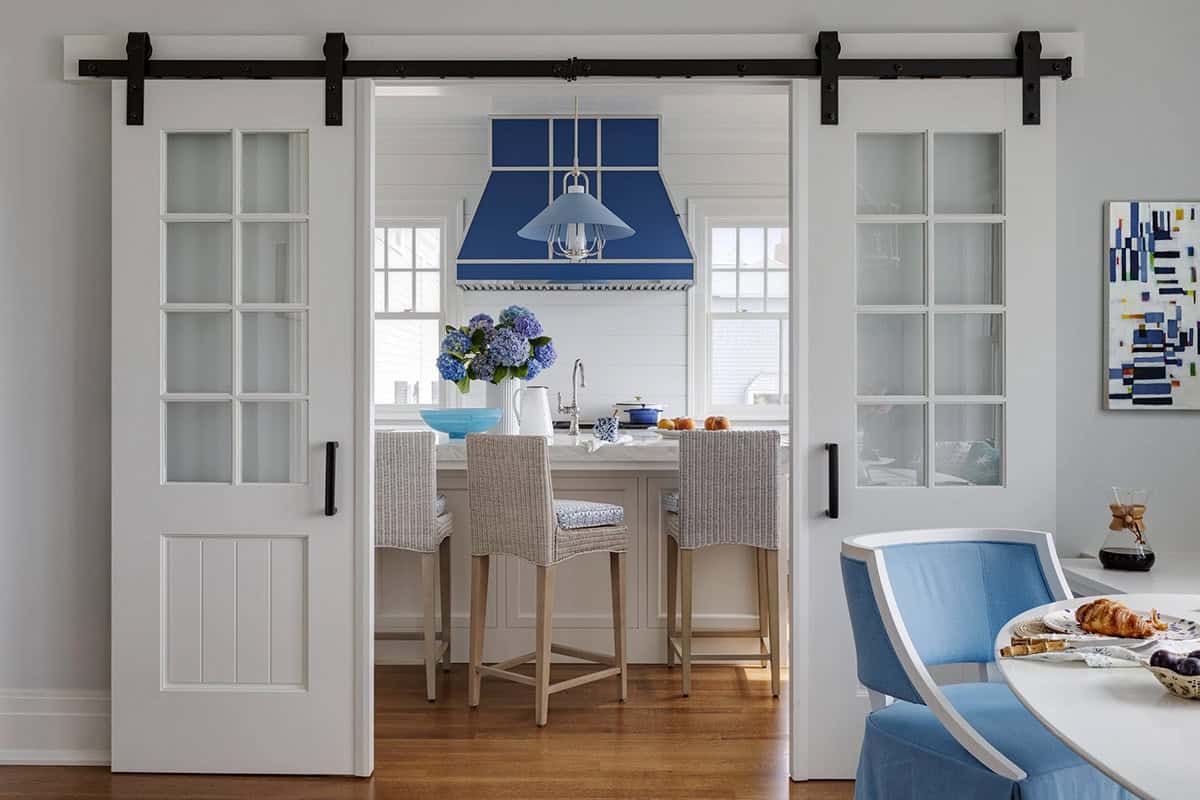 Barn doors open to kitchen with cobalt blue range hood