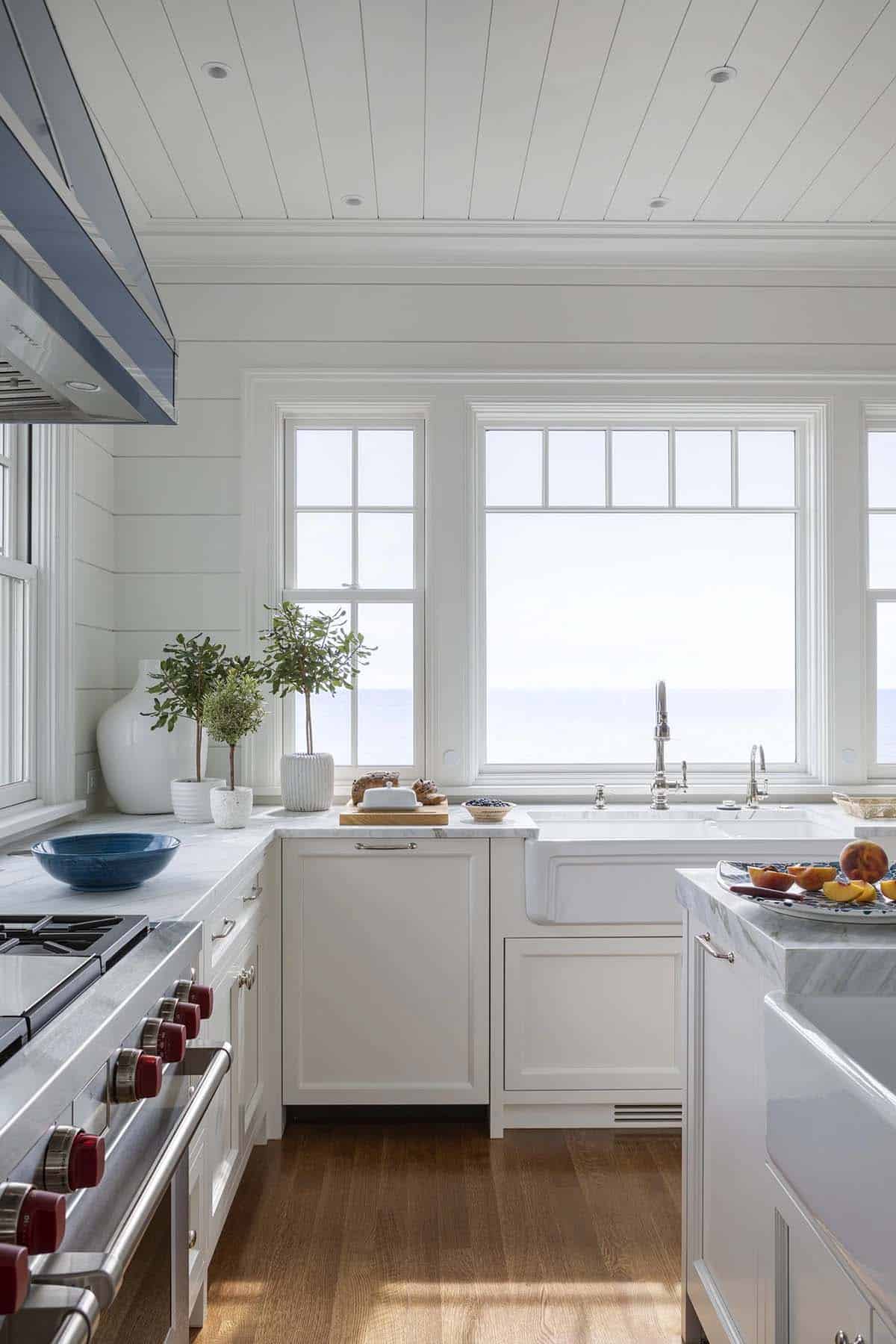 White kitchen sink and range framed by ocean-view windows