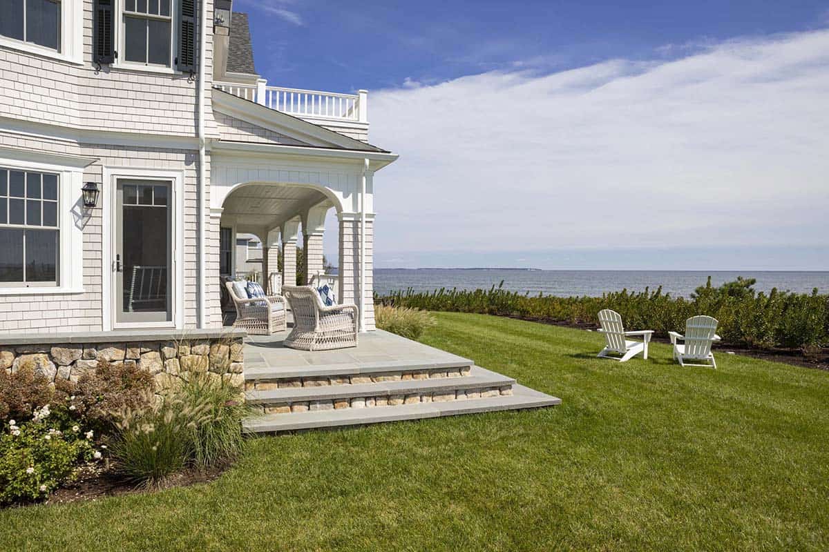 Bluestone patio with wicker chairs overlooking coastal lawn and sea