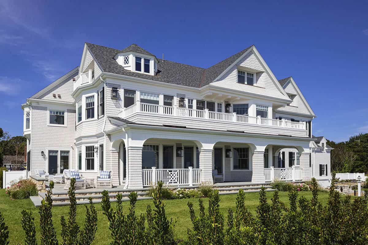 Shingle-style beach home with covered porch and manicured lawn