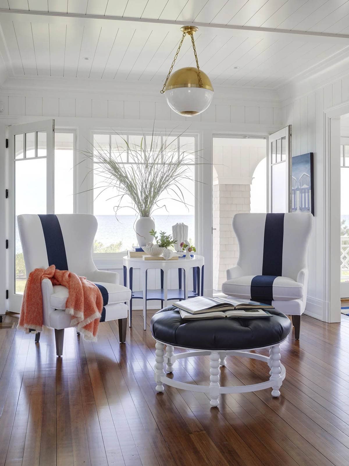 Striped wingback chairs and brass pendant in sunroom seating area